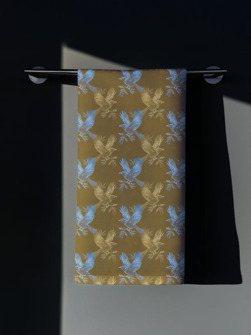 Set of four golden cloth napkins featuring alternating powder blue and metallic gold ravens in flight, sized 18x18 inches.